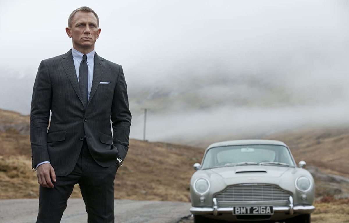 James Bond - Daniel Craig in una scena di Skyfall, con sullo sfondo la nota Aston Martin